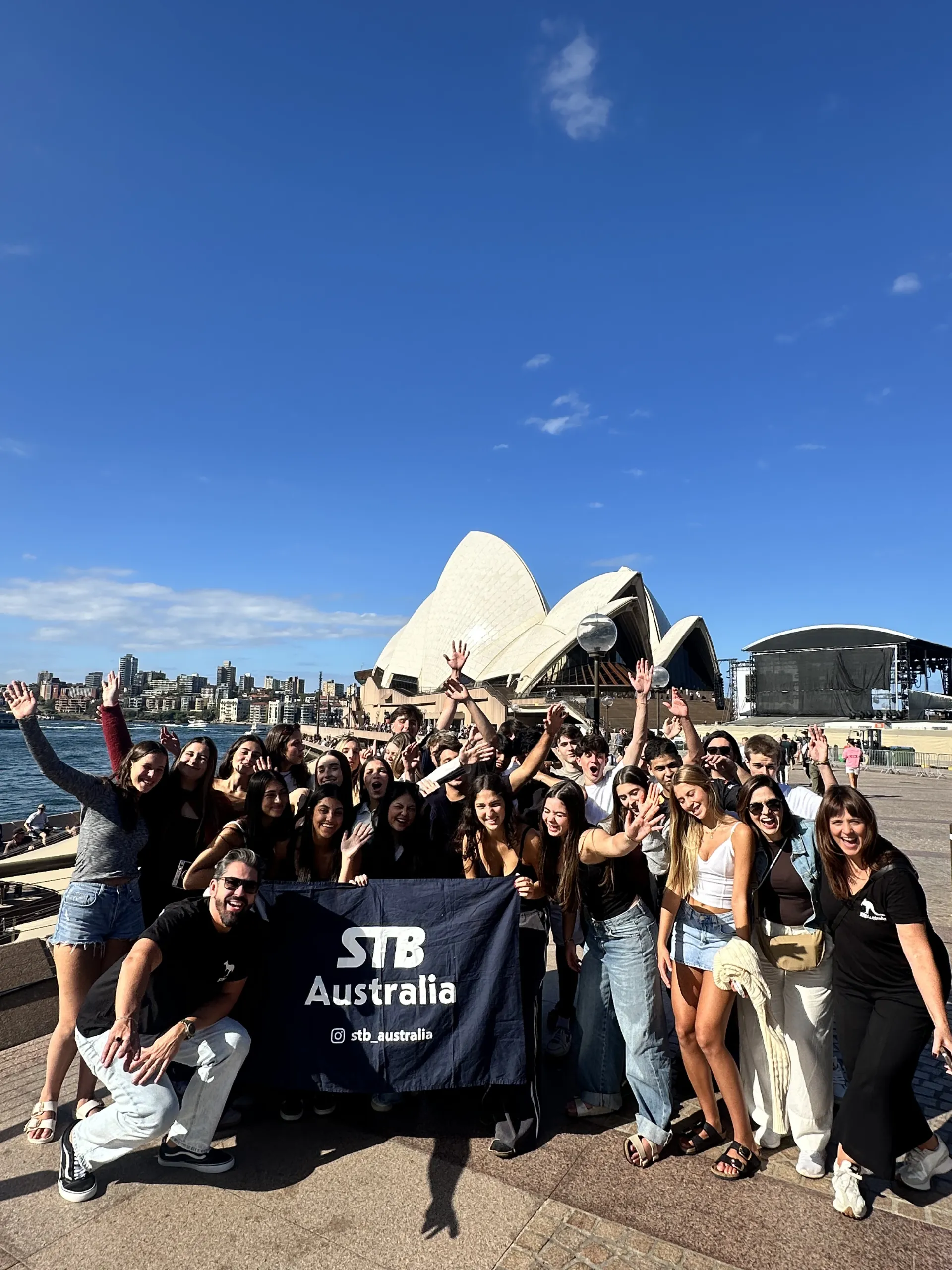 Estudante brasileira sendo recebida em Sydney com a Harbour Bridge ao fundo